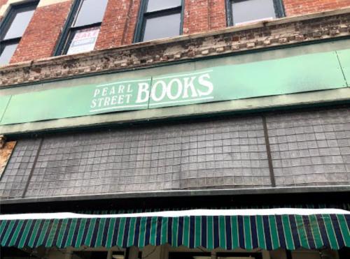 Sign for "Pearl Street Books" on a brick building, with a green awning and a "Sale" sign in the window.