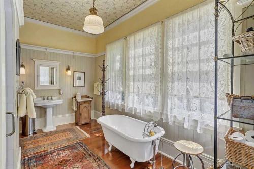 Bright bathroom featuring a vintage clawfoot tub, elegant curtains, and warm wooden accents.