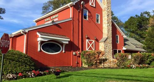 A red barn-style building with a stone chimney, surrounded by green grass and colorful flower beds.
