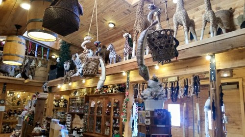 A rustic shop interior filled with animal figurines, wooden decor, and various hanging items.