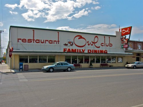 Exterior of the Owl Club restaurant, featuring a retro sign and family dining theme, with cars parked outside.