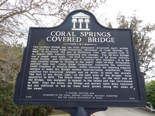 Sign detailing the history of the Coral Springs Covered Bridge, including its construction and significance.