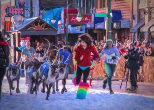 A colorful race scene with runners and reindeer on snow, surrounded by a cheering crowd in a festive atmosphere.