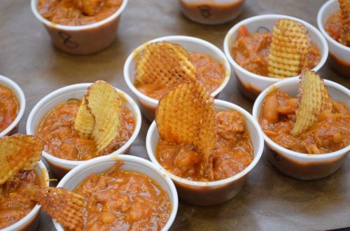 Small cups of chili topped with waffle potato chips, arranged on a tray.