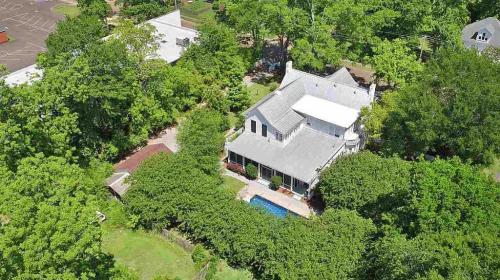 Aerial view of a house surrounded by lush greenery and a swimming pool in the backyard.