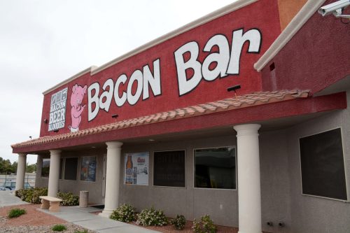 Exterior of a restaurant called "Bacon Bar," featuring a large sign with a pink pig and bold lettering.