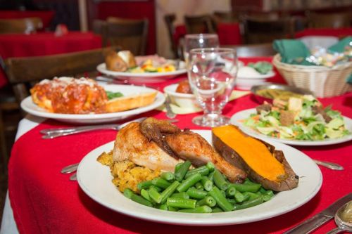 A table set with a delicious meal featuring roasted chicken, sweet potato, green beans, salad, and pasta dishes.