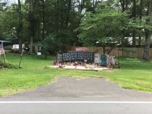 A quirky outdoor display with a sign reading "Barbecue Beach," surrounded by trees and various decorations.