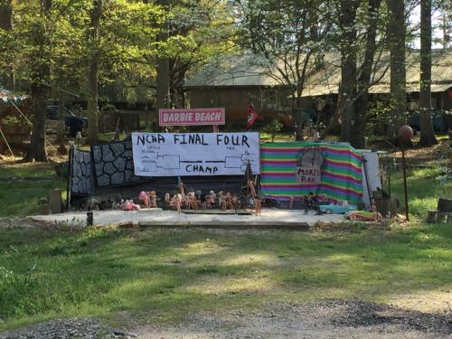 A whimsical outdoor display featuring a makeshift NCAA Final Four bracket and colorful decorations in a wooded area.
