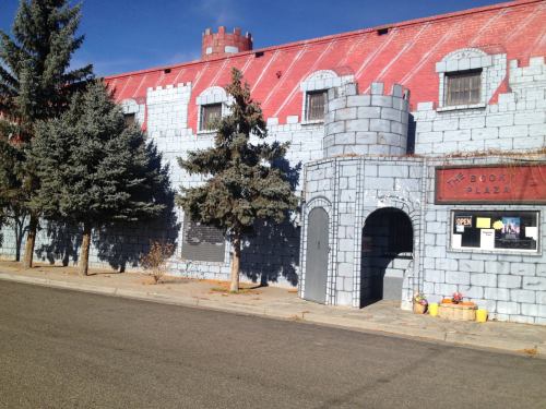 A whimsical building resembling a castle, featuring stone-like walls, a red roof, and a sign for "The Book Plaza."