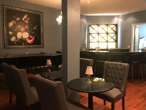 Cozy restaurant interior with elegant seating, a large floral painting, and a stylish bar area in the background.
