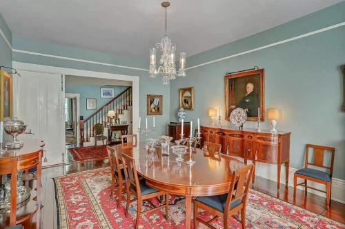 Elegant dining room featuring a round table, antique chairs, a chandelier, and classic artwork on the walls.
