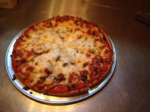 A freshly baked pizza with melted cheese and toppings, sliced into equal pieces on a silver tray.