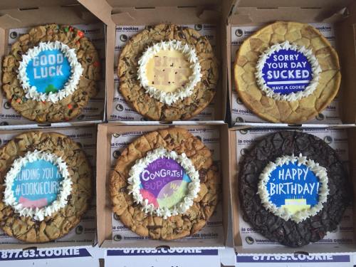A variety of large cookies in boxes, each with colorful messages like "Good Luck," "Happy Birthday," and "Congrats!"