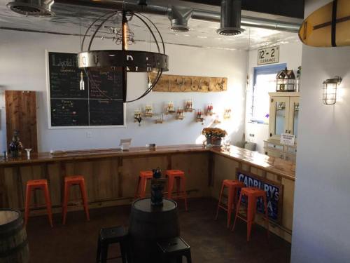 A cozy bar interior featuring a wooden counter, orange stools, and a chalkboard menu on the wall.