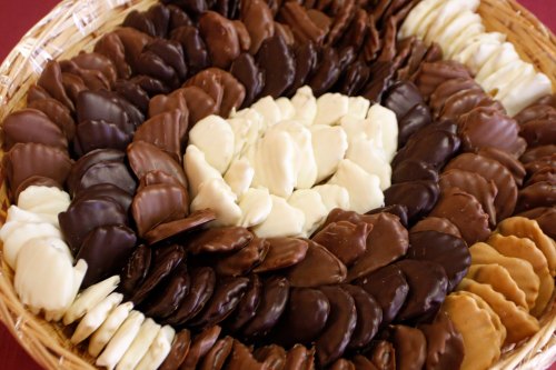 A woven basket filled with an assortment of chocolate-covered treats in dark, milk, and white chocolate.
