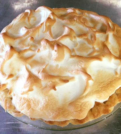 A golden-brown meringue pie with a fluffy, textured topping in a glass pie dish.