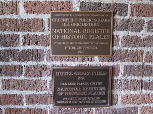 Two bronze plaques on a brick wall, marking Hotel Greenfield's historic status and its place on the National Register of Historic Places.