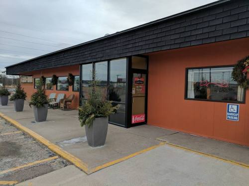 Exterior of a restaurant with orange walls, large planters, and a Coca-Cola sign near the entrance.