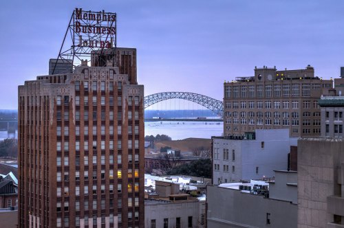 View of Memphis skyline at dusk, featuring the Memphis Business Building and a bridge over the river.