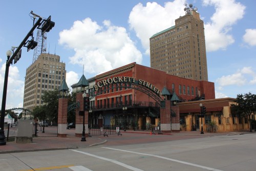 Crockett Street entrance with historic buildings and a blue sky in the background. Traffic lights visible.