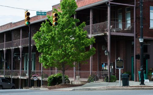 Historic brick buildings with balconies, a green tree, and traffic lights at the intersection of Spring Park.