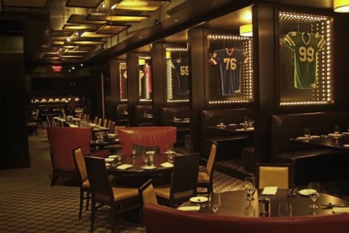 A stylish restaurant interior featuring framed sports jerseys, dim lighting, and elegant dining tables.