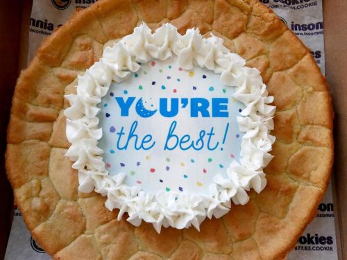 A large cookie cake with white frosting and a center message that reads "YOU'RE the best!" surrounded by colorful confetti.