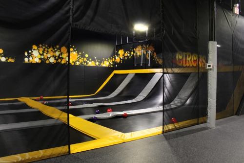 Indoor trampoline park featuring multiple trampolines with colorful balls scattered across the surface.
