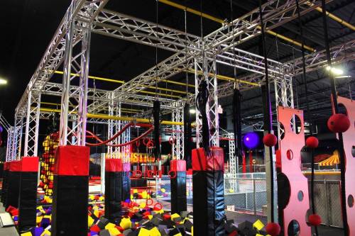 Indoor adventure park featuring climbing structures, foam pits, and colorful obstacles for active play.