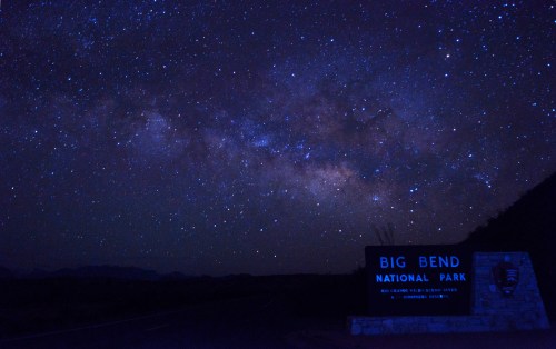 A starry night sky over the Big Bend National Park sign, showcasing the Milky Way's vibrant colors.