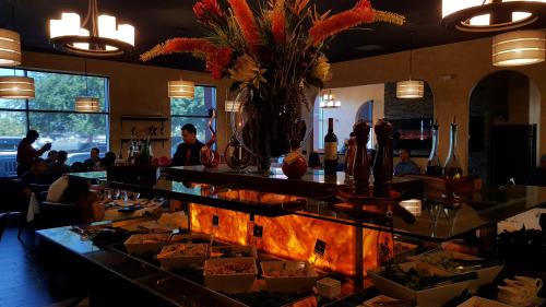 A vibrant restaurant interior featuring a buffet with colorful dishes, elegant decor, and diners enjoying their meals.