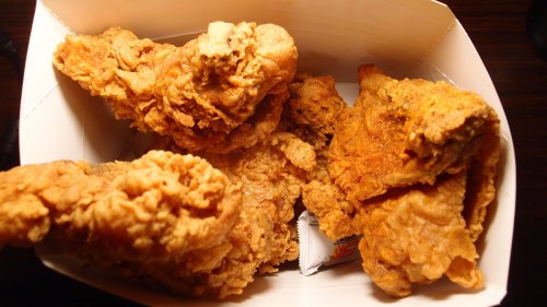 A box filled with several pieces of crispy, golden-brown fried chicken.
