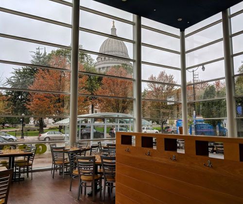 View from a modern café with large windows, showcasing autumn trees and a dome building in the background.