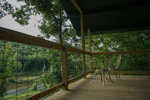 A serene porch with two chairs overlooking a lush green landscape and a calm water view.