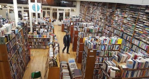A spacious bookstore filled with tall shelves of books and a few people browsing the aisles.