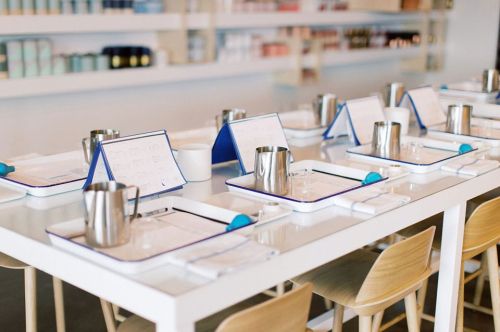 A neatly arranged table with menus, glasses, and metal pitchers, set for a dining experience in a modern space.