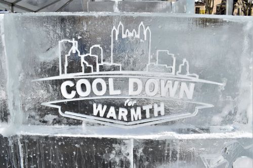 Ice sculpture featuring the text "COOL DOWN for WARMTH" with a city skyline silhouette in the background.
