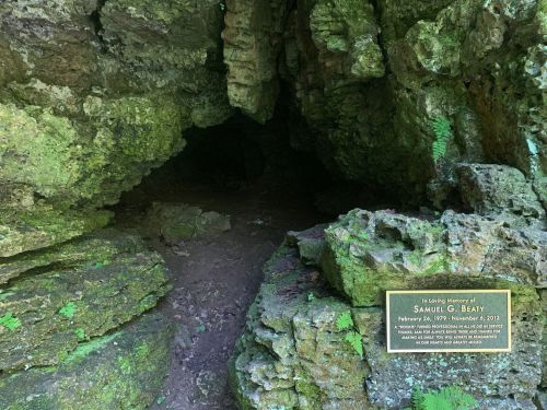 A cave entrance with rocky walls and a plaque honoring Samuel G. Beatty, dated February 20, 1875 - November 4, 1932.