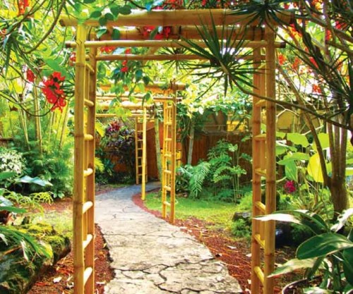 A serene garden path framed by bamboo arches and lush greenery, adorned with vibrant flowers.