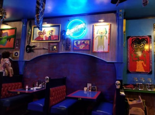 Colorful restaurant interior featuring vibrant artwork, neon signs, and cozy booths with a lively atmosphere.