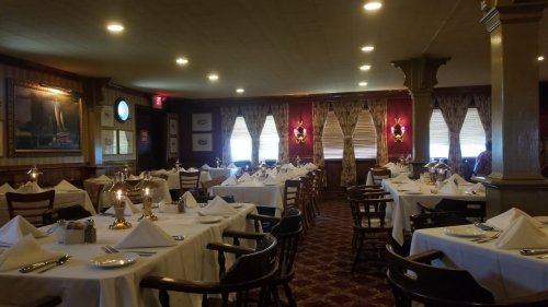Elegant restaurant interior with white tablecloths, neatly set tables, and warm lighting.
