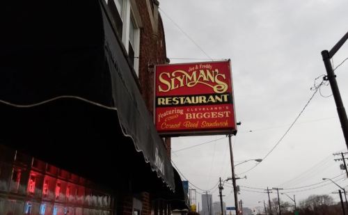 Sign for Slyman's Restaurant in Cleveland, featuring the "biggest corned beef sandwich." Overcast sky in the background.