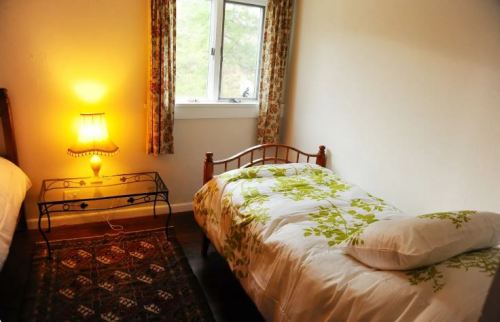 Cozy bedroom with two beds, a lamp, and a window, featuring floral bedding and patterned curtains.