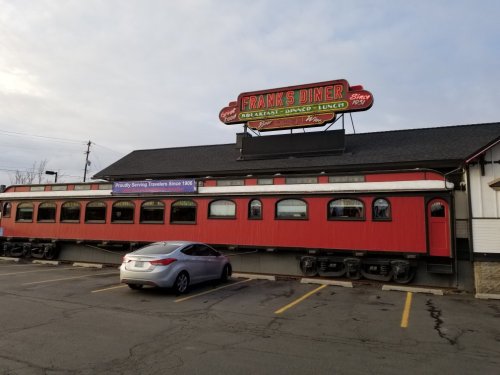 Exterior of Frank's Diner, a red and white building with a sign, parked car in front, and a clear sky above.