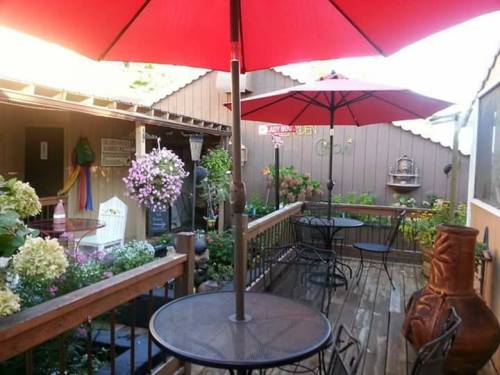 A cozy outdoor patio with red umbrellas, tables, and vibrant flowers, creating a welcoming atmosphere.