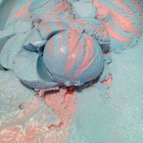 Close-up of blue and pink swirled ice cream, with scoops and a creamy texture.