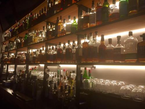A dimly lit bar shelf filled with various bottles of liquor and glassware, creating a warm, inviting atmosphere.