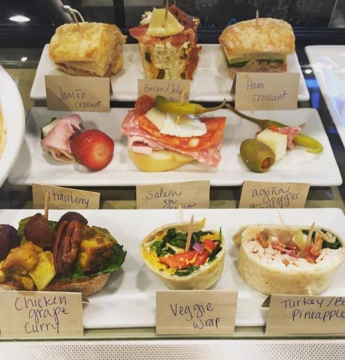 A display of assorted sandwiches and wraps, labeled with ingredients, including chicken curry, veggie wrap, and turkey.