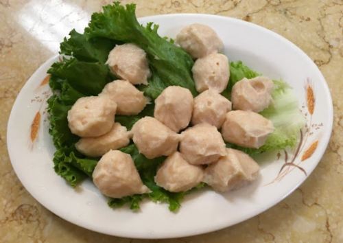 A plate of light-colored dumplings arranged on a bed of fresh lettuce leaves.